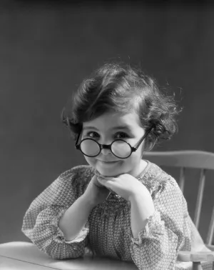 1930s portrait little girl smiling wearing big round eyeglasses looking at camera